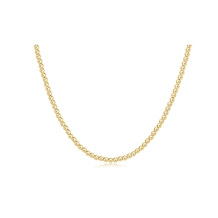 A delicate yellow gold chain necklace with small, tightly spaced round beads, displayed in a U-shape against a solid white background.
