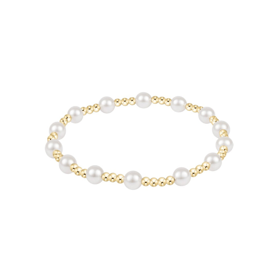 A delicate beaded bracelet featuring alternating large white pearls and small polished gold beads, arranged in a horizontal oval on a solid white background.