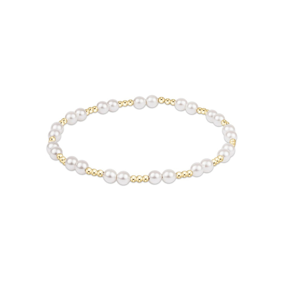 A delicate beaded stretch bracelet featuring white pearls and small gold metallic beads, displayed on a clean white background.