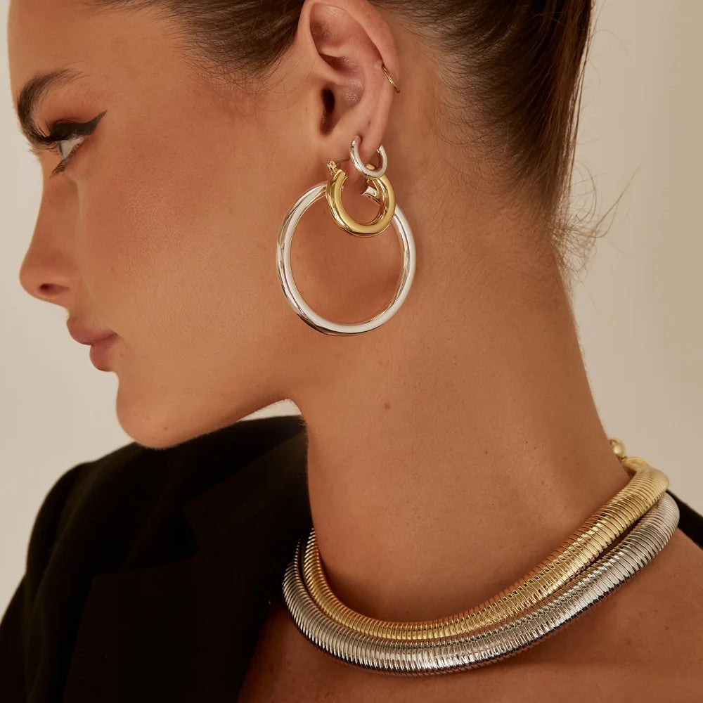 Model wearing gold and silver bold jewelry.