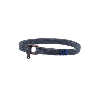 A dark gray braided rope bracelet with a bronze-toned metal toggle clasp and a small blue stitched accent on a white background.