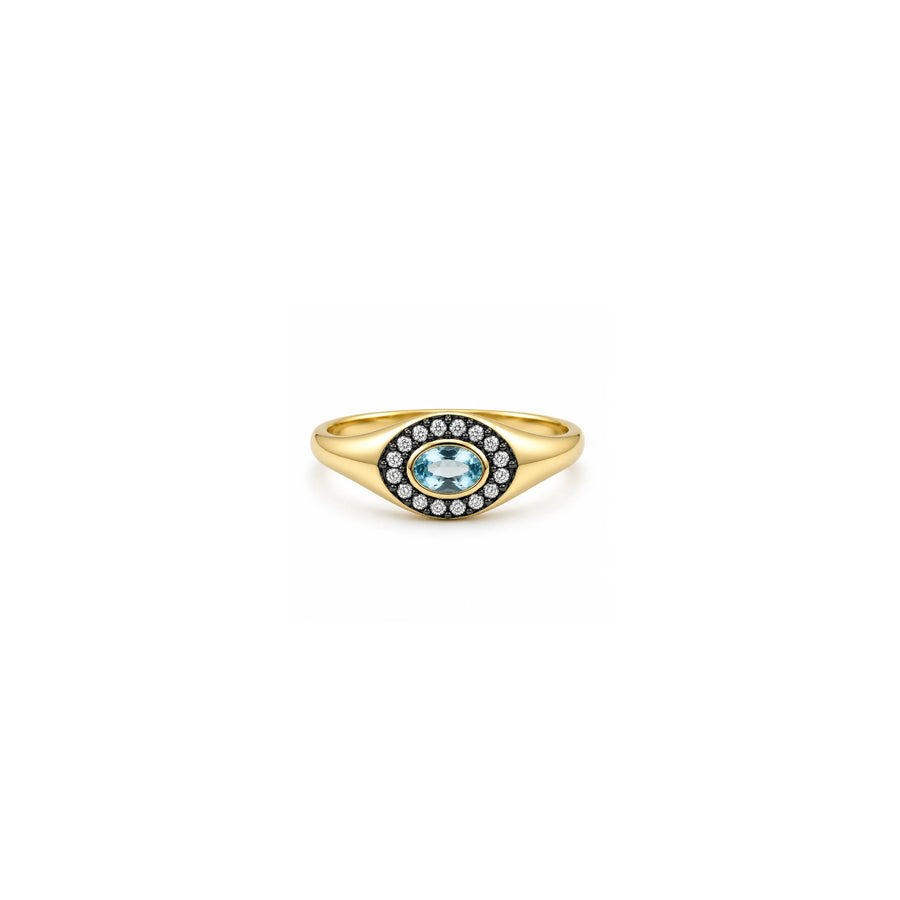 A gold signet ring featuring an oval light blue topaz center stone surrounded by a halo of small clear stones, set against a plain white background.