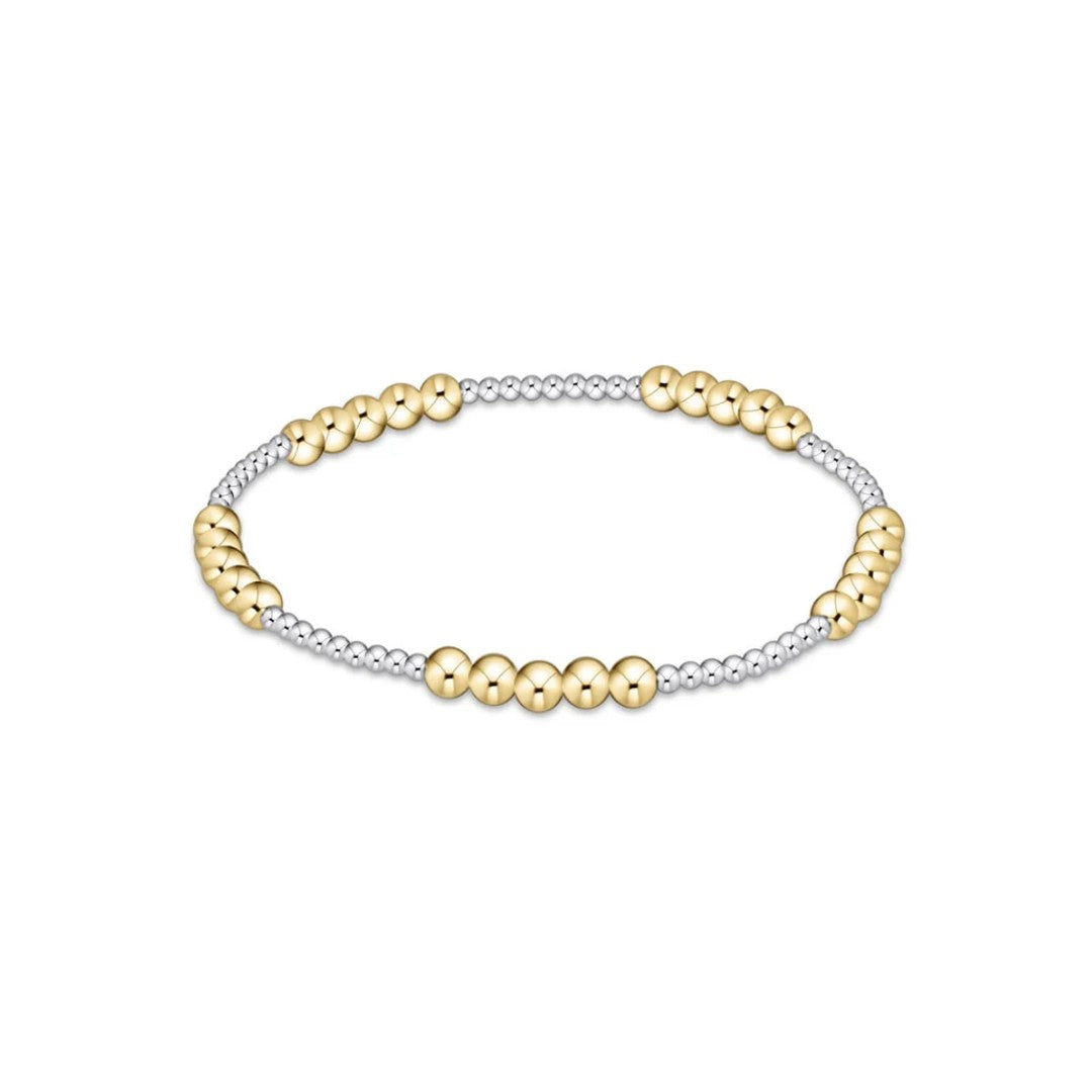 A two-tone beaded stretch bracelet featuring polished yellow gold round beads alternating with small silver-toned metallic beads, shown on a plain white background.