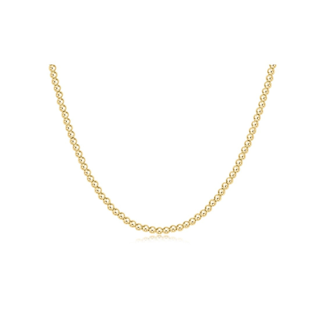 A delicate yellow gold chain necklace with small, tightly spaced round beads, displayed in a U-shape against a solid white background.
