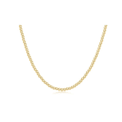 A delicate yellow gold chain necklace with small, tightly spaced round beads, displayed in a U-shape against a solid white background.