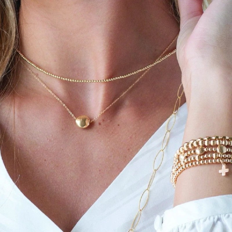 Close-up of a person wearing gold necklaces and bracelets.