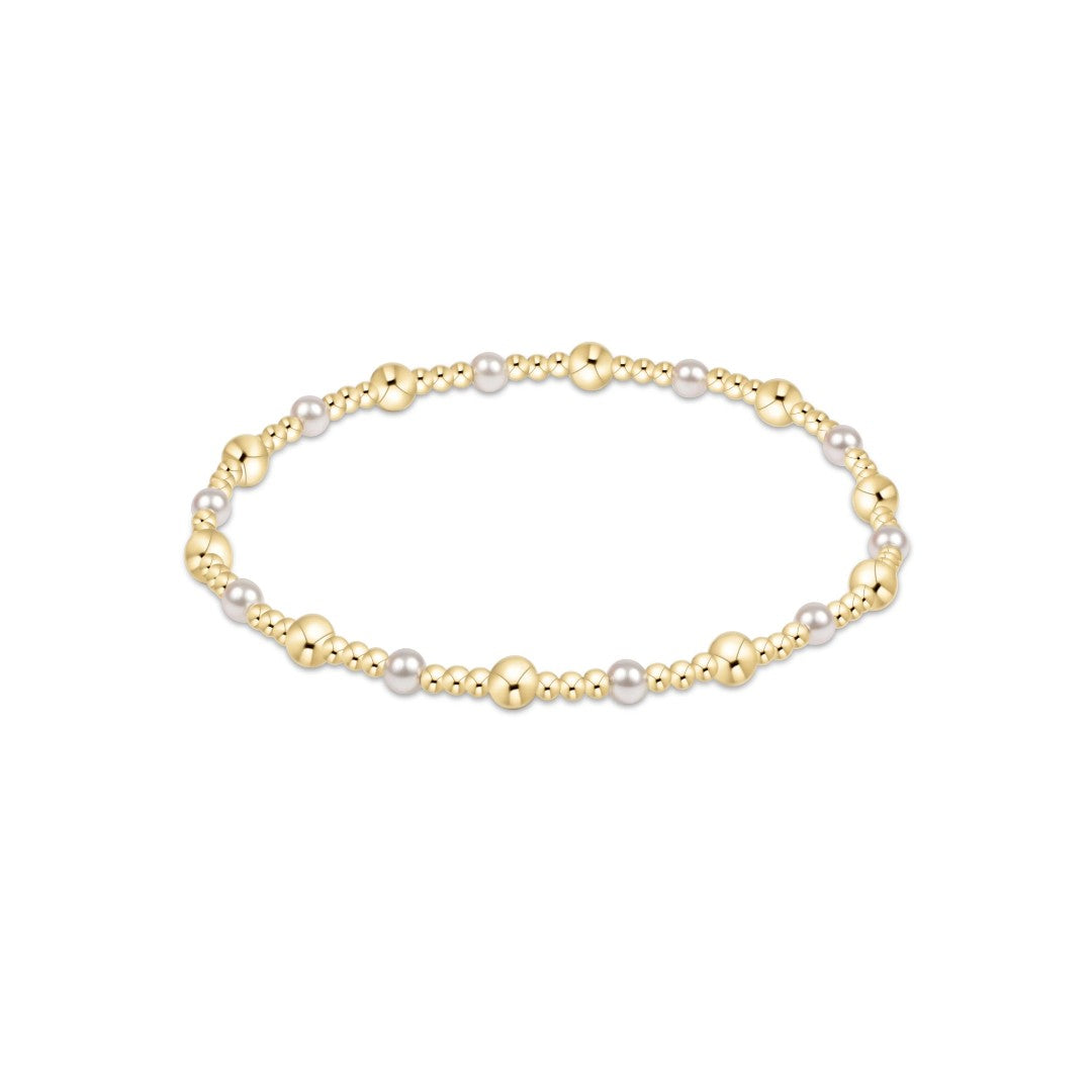 A delicate beaded bracelet featuring alternating polished gold beads and small white pearls, displayed on a clean white background.