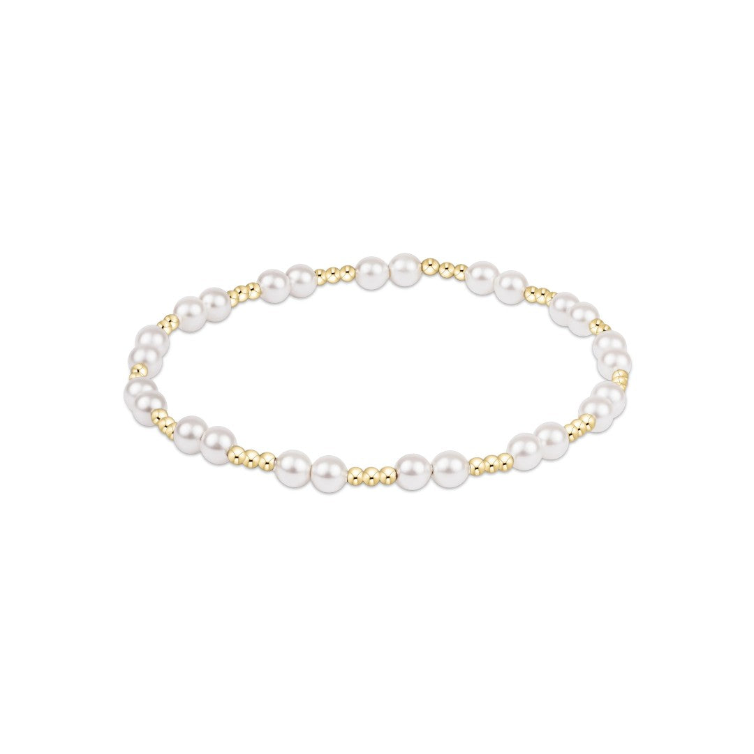 A delicate beaded stretch bracelet featuring white pearls and small gold metallic beads, displayed on a clean white background.