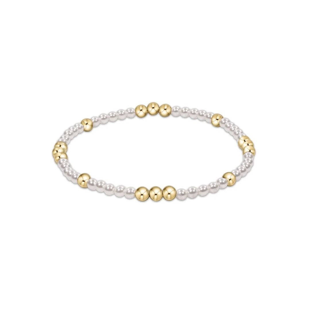 A delicate beaded stretch bracelet featuring small white pearl-like beads alternating with polished gold metallic beads, shown on a plain white background.