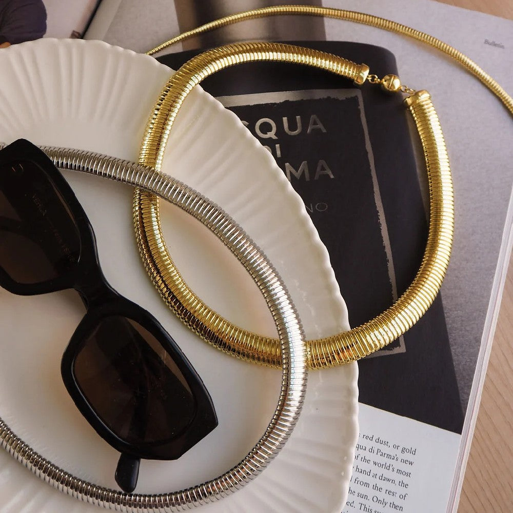 Flexible necklaces on top of book with sunglasses.