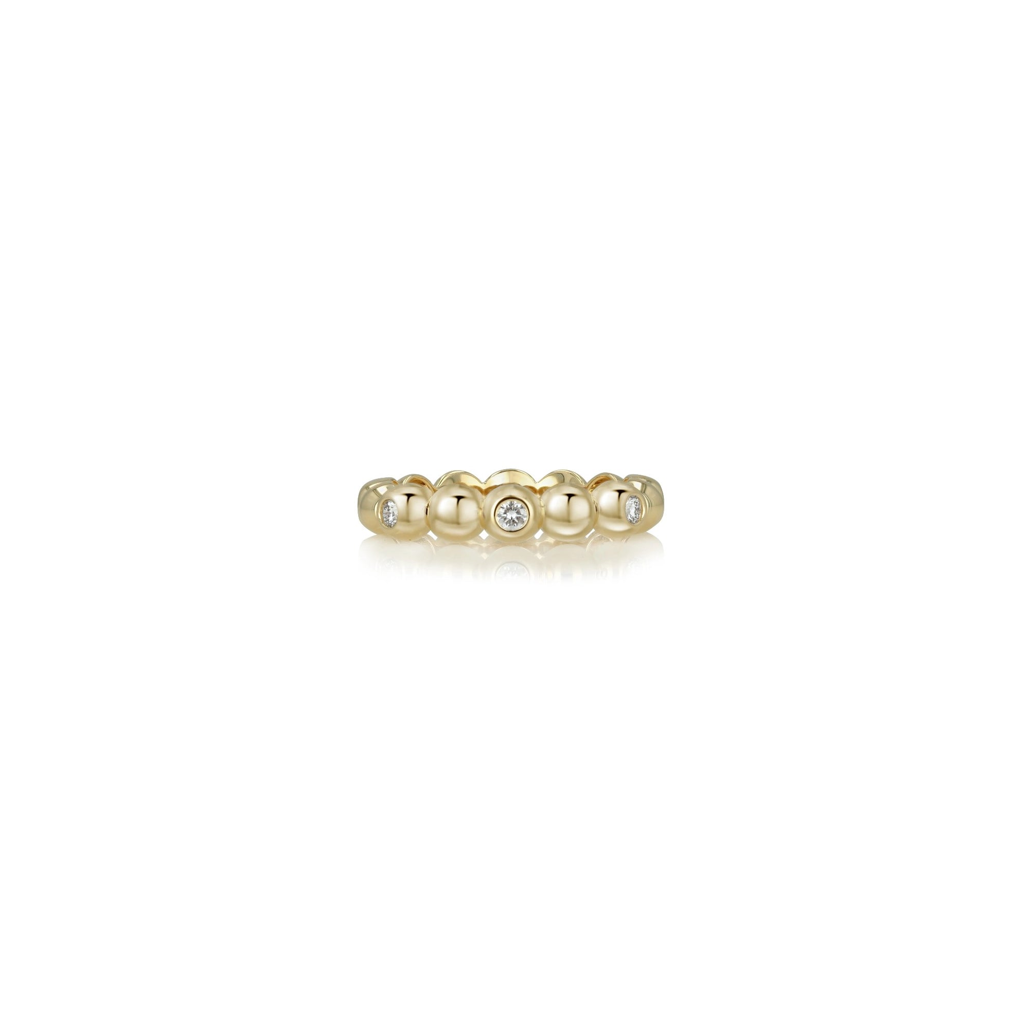 A delicate yellow gold beaded band ring with a single round clear gemstone in the center, displayed on a clean white background with a soft reflection.