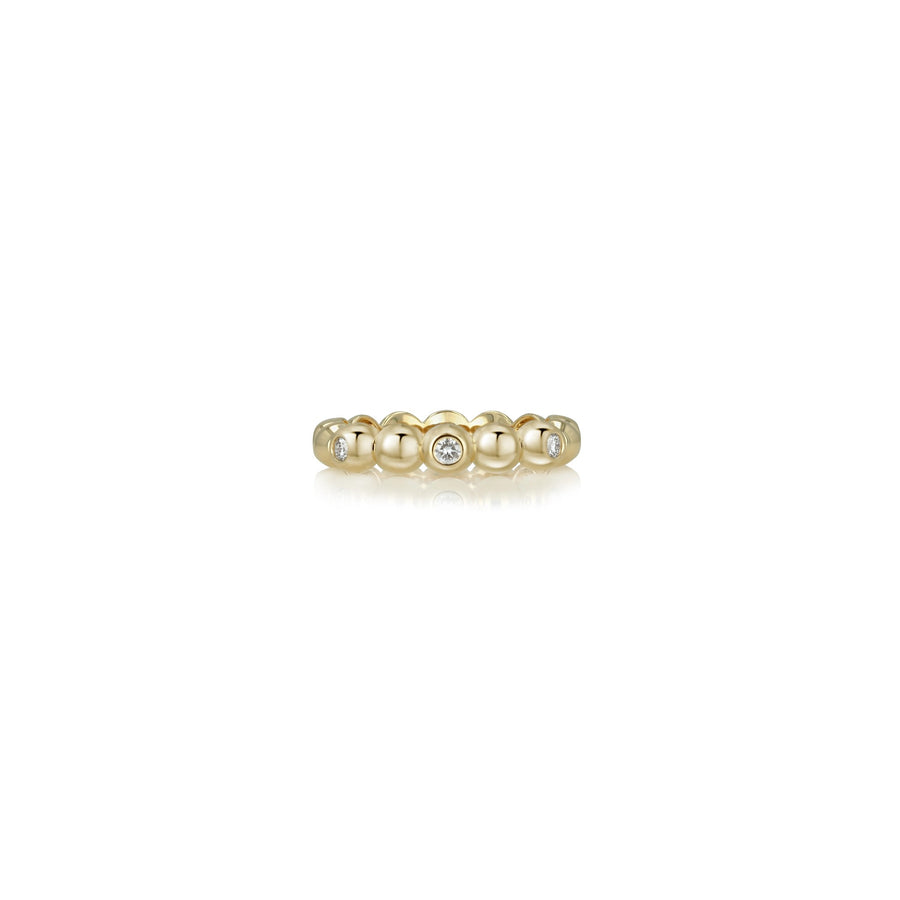 A delicate yellow gold beaded band ring with a single round clear gemstone in the center, displayed on a clean white background with a soft reflection.
