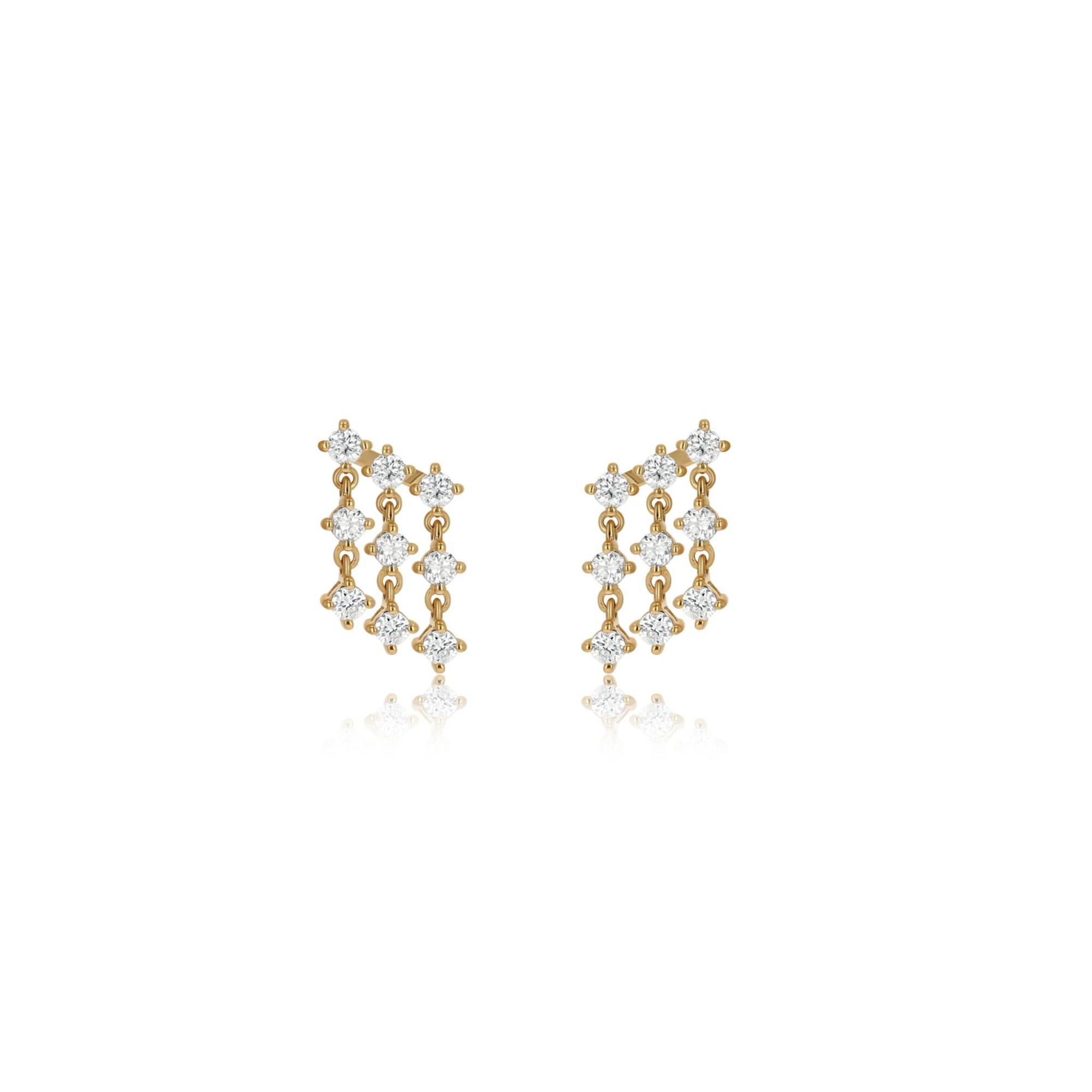 A pair of gold stud earrings set with clear gemstones, arranged in three vertical rows of three stones each, on a solid white background with a soft reflection below.