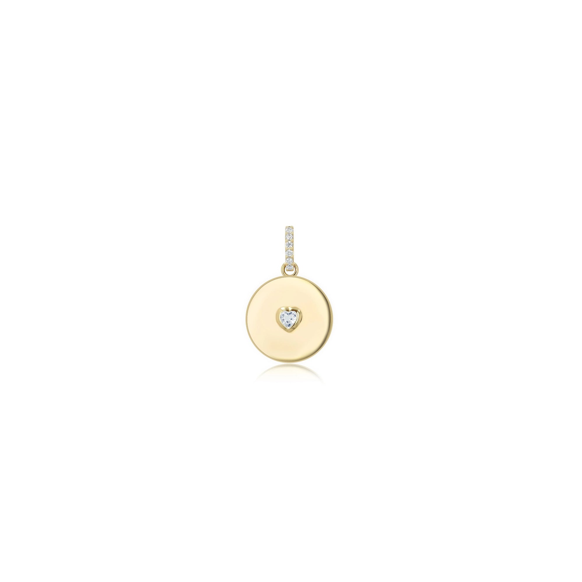 A gold round disc pendant charm featuring a small heart-shaped clear gemstone at its center, set against a solid white background.