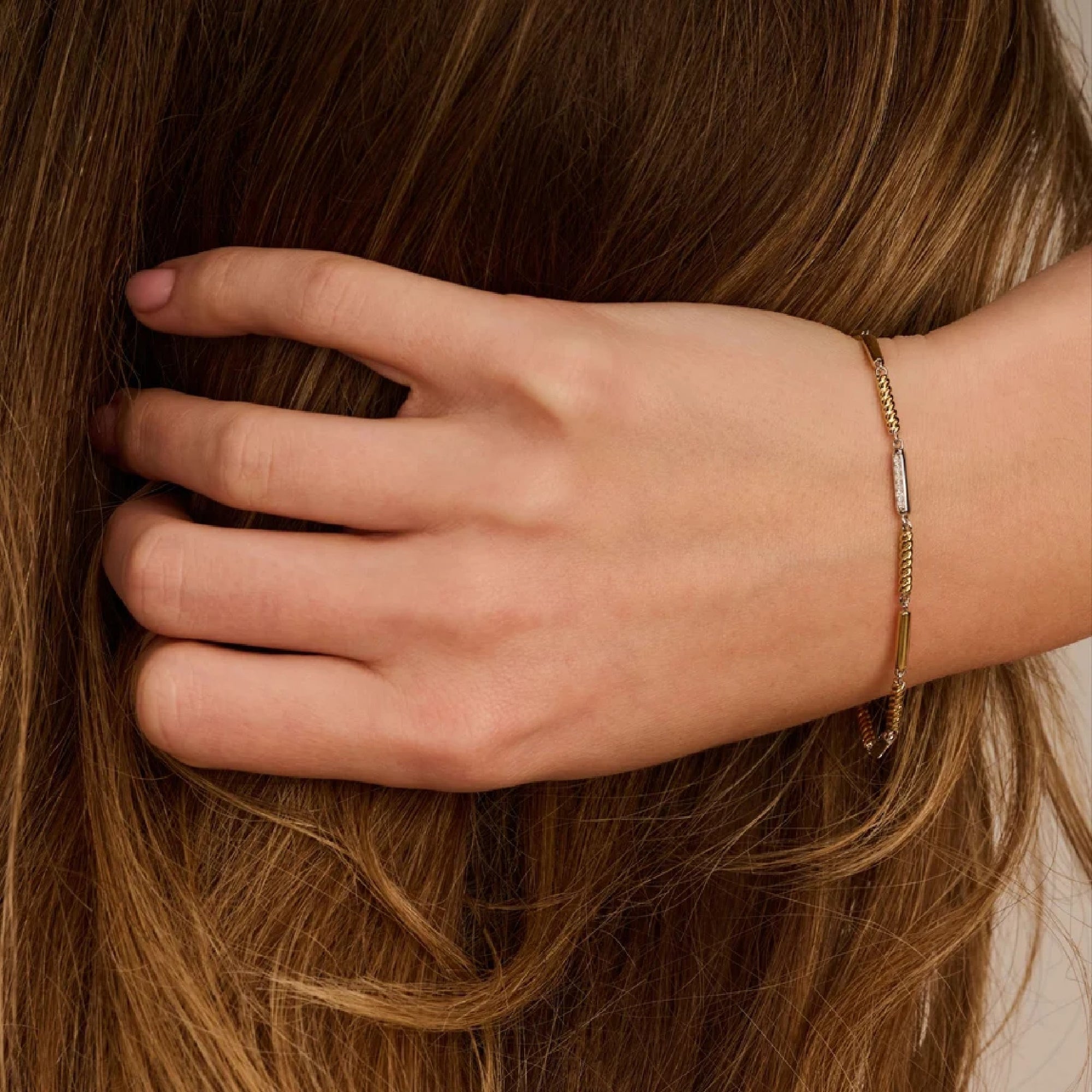 Woman with brown hair and close-up of Ti Sento bar bracelet links, alternating rope texture and pavé zirconia detail